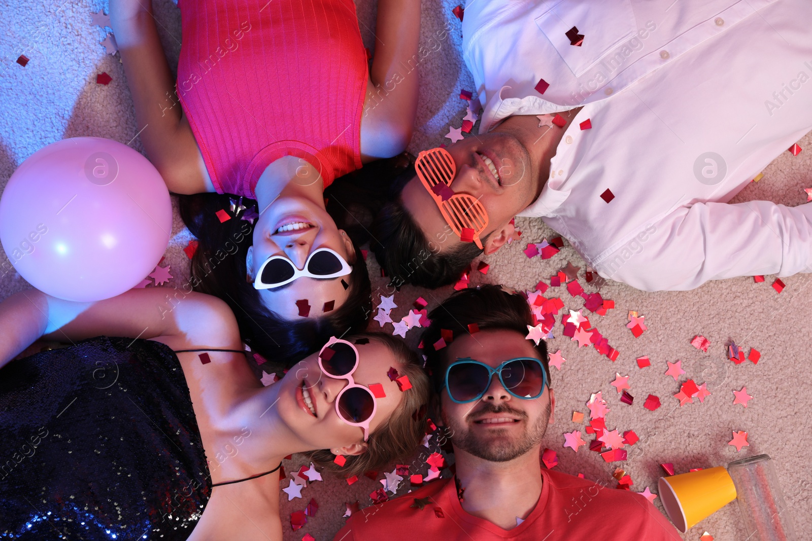 Photo of Group of friends lying on messy floor after party, top view