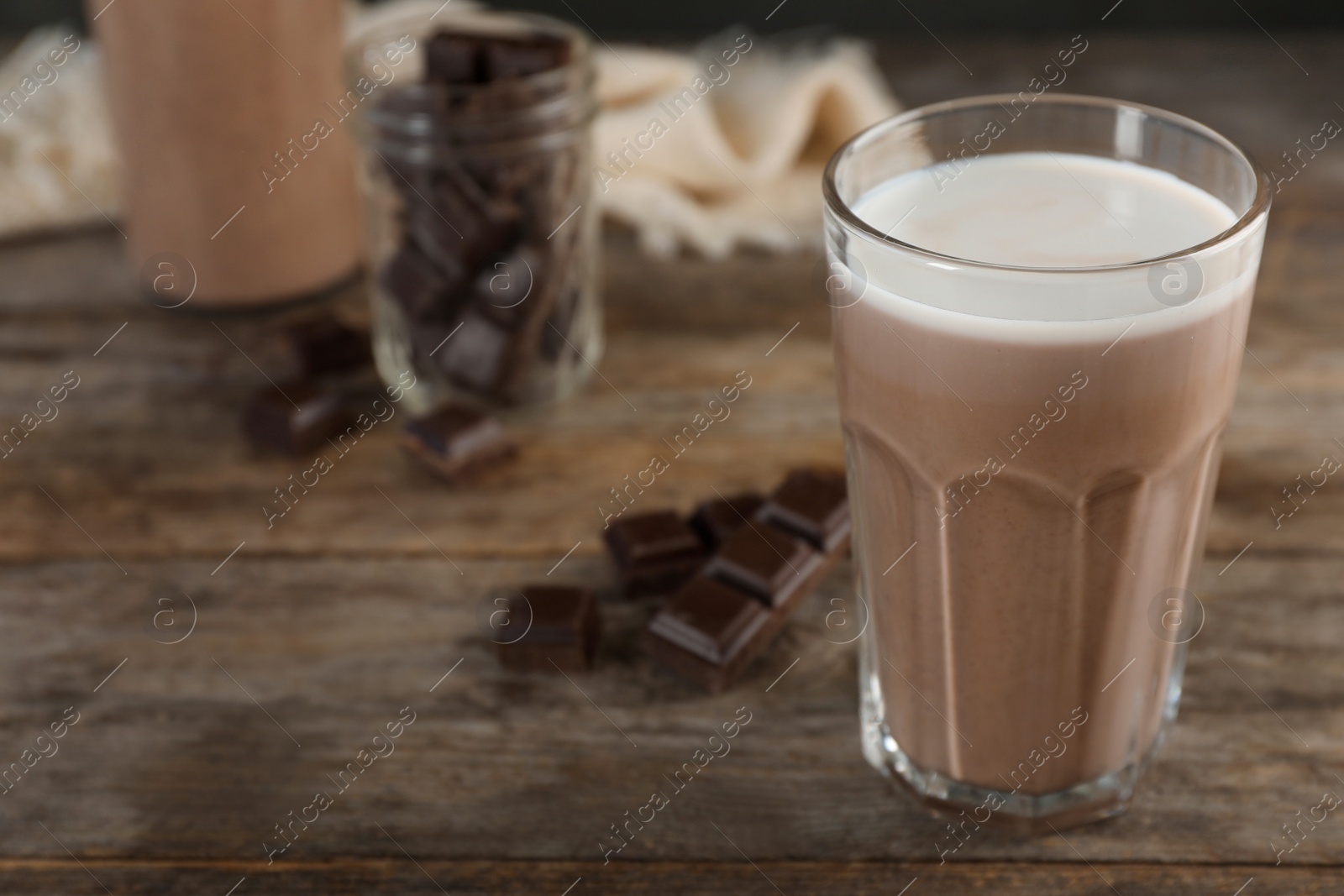 Photo of Glass of chocolate milk on wooden table, closeup. Space for text