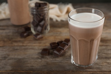 Glass of chocolate milk on wooden table, closeup. Space for text