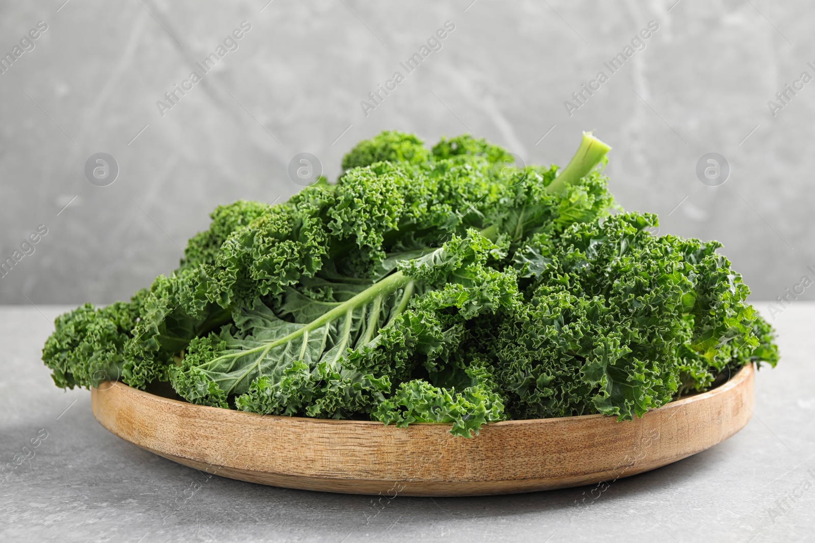 Photo of Fresh kale leaves on light grey table, closeup