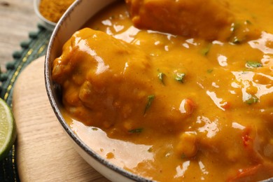Photo of Tasty chicken curry on wooden table, closeup