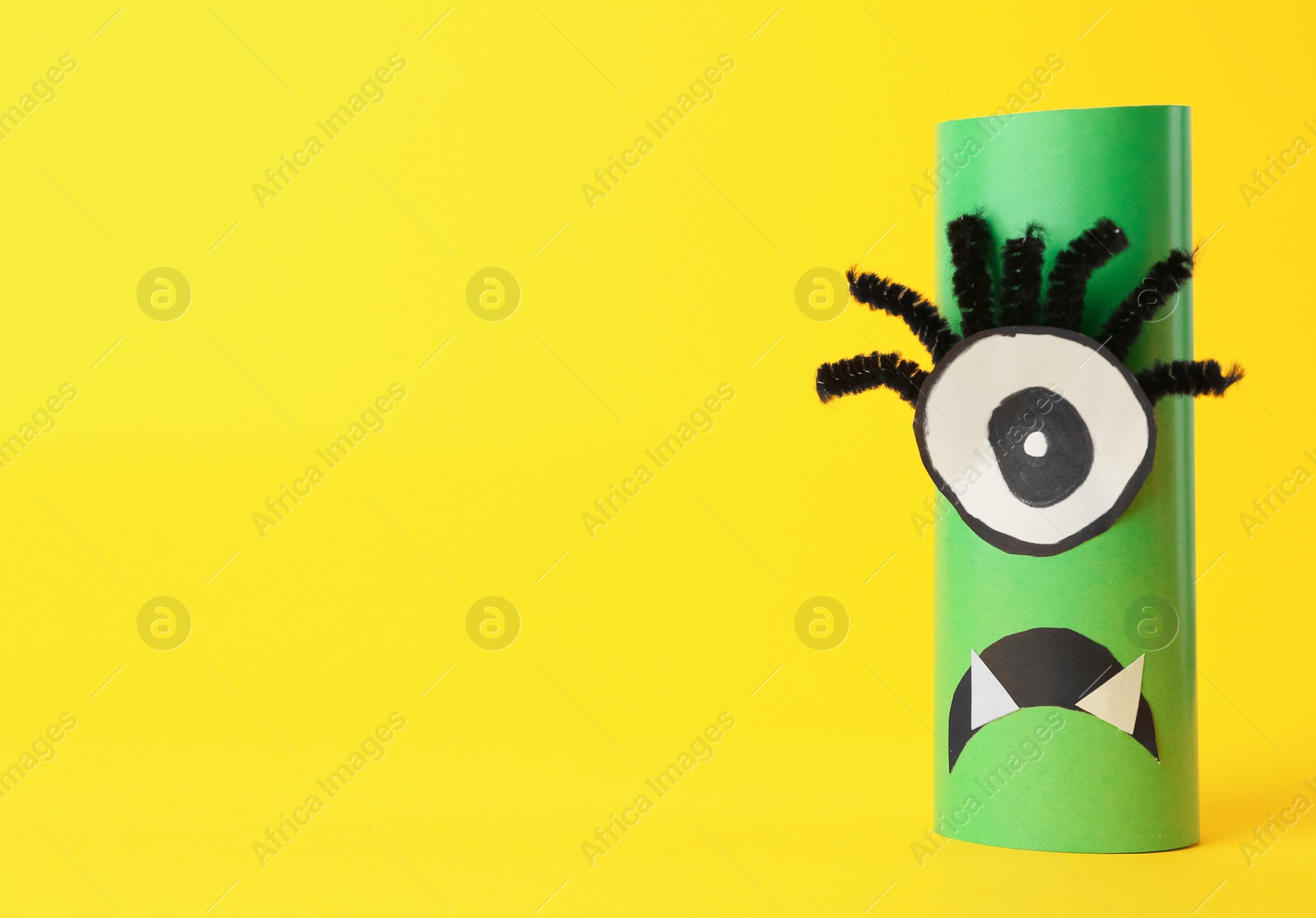 Photo of Funny green monster on yellow background, space for text. Halloween decoration