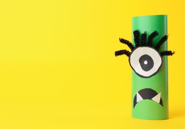 Photo of Funny green monster on yellow background, space for text. Halloween decoration
