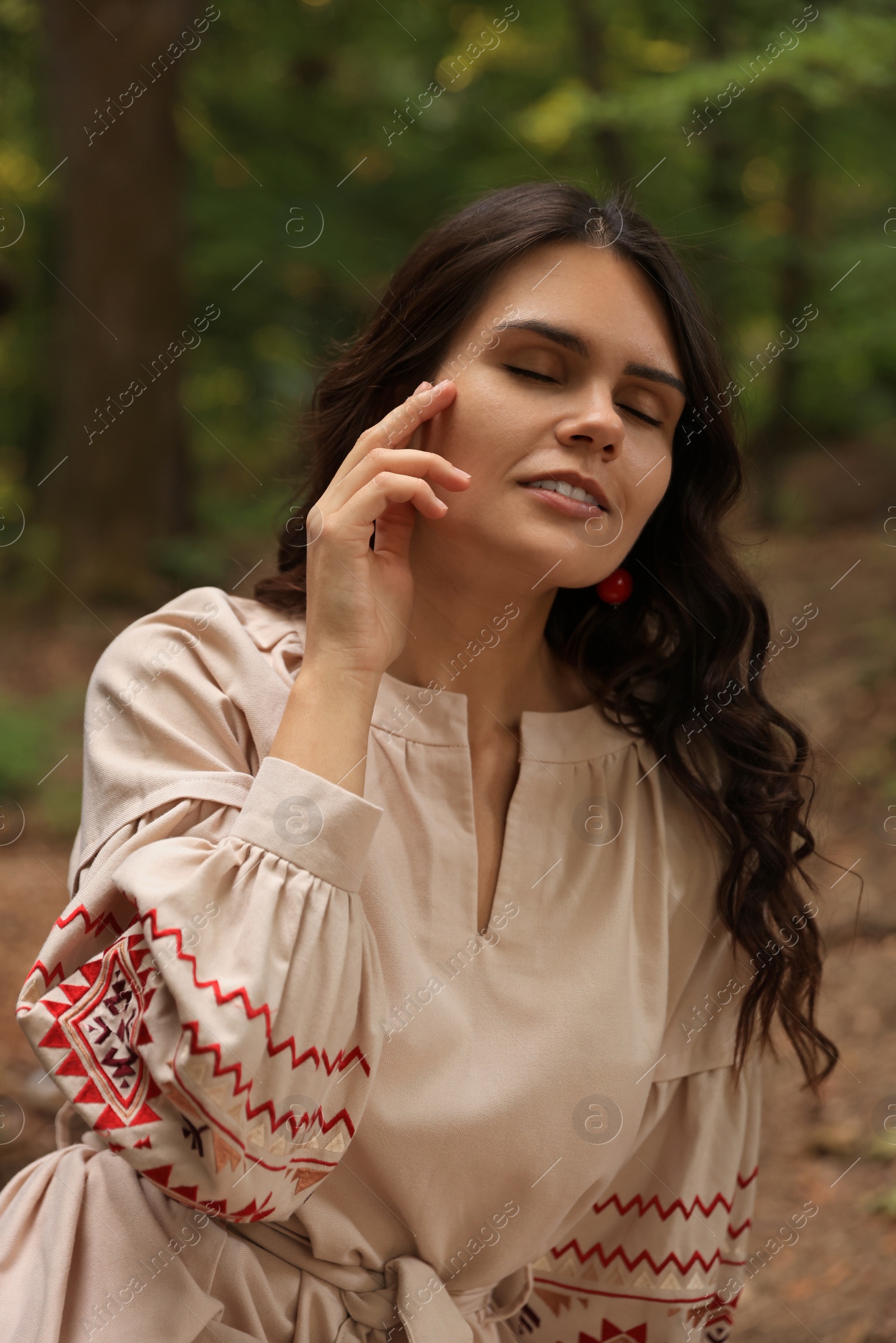 Photo of Beautiful woman in embroidered dress outdoors. Ukrainian national clothes