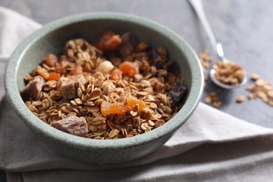 Tasty granola in bowl and napkin on gray table, closeup