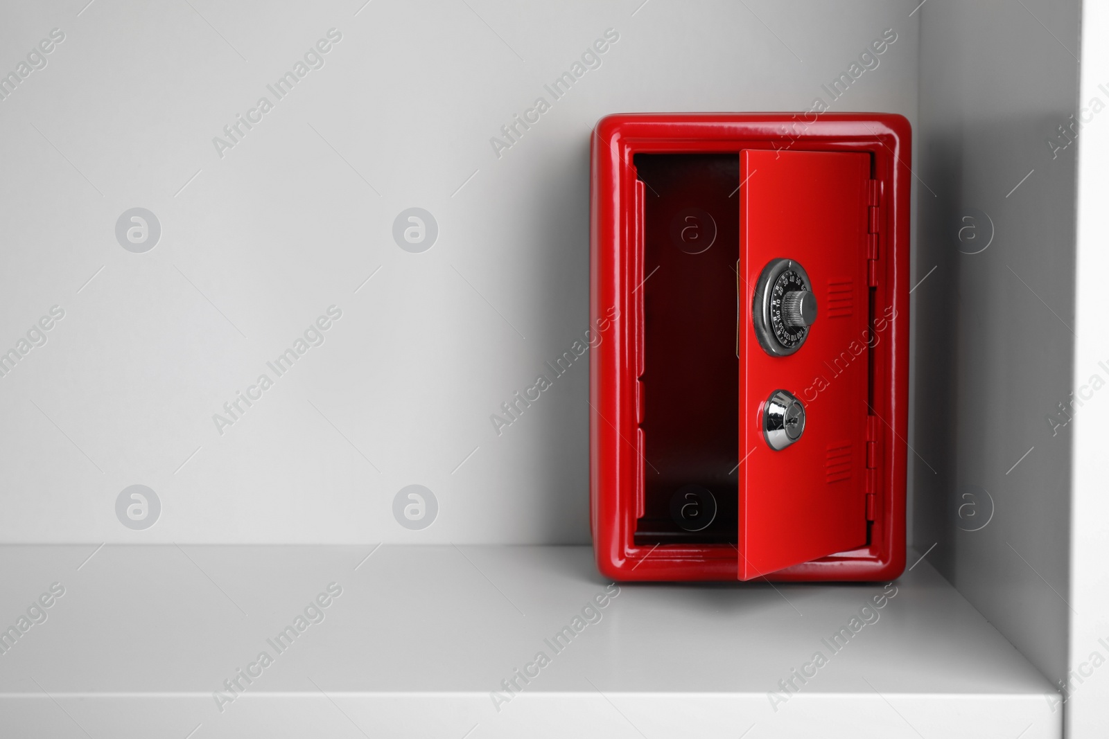 Photo of Red steel safe with mechanical combination lock on shelf. Space for text