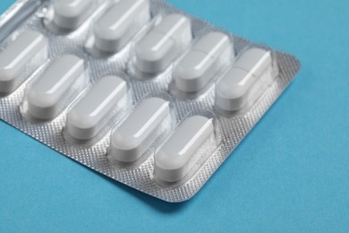 Pills in blister on blue background, closeup