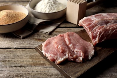 Photo of Cooking schnitzel. Raw pork slices and other ingredients on wooden table, closeup