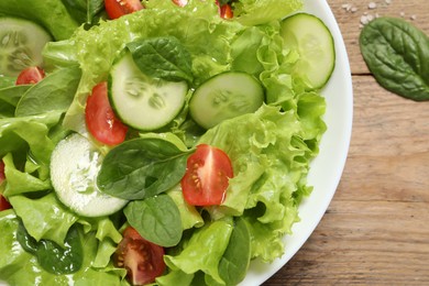 Photo of Delicious salad in bowl on wooden table, top view