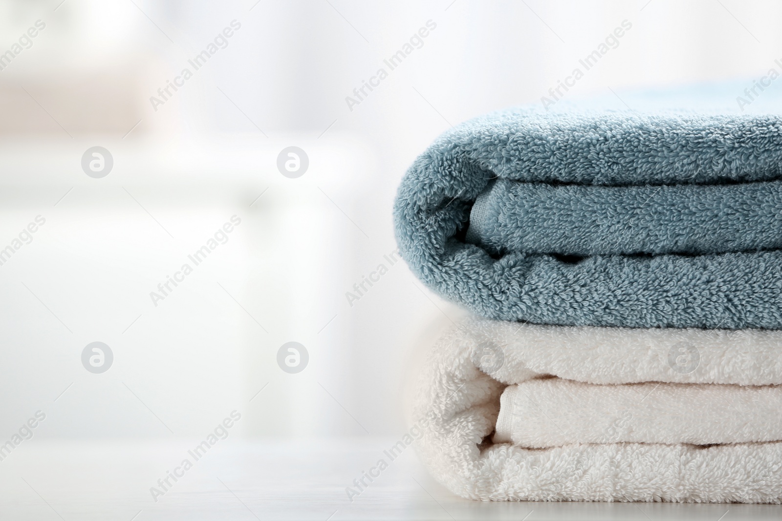 Photo of Stack of fresh towels on table, closeup. Space for text