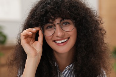 Portrait of beautiful woman in glasses indoors. Attractive lady smiling and looking into camera