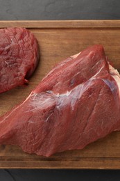 Pieces of raw beef meat on black table, top view