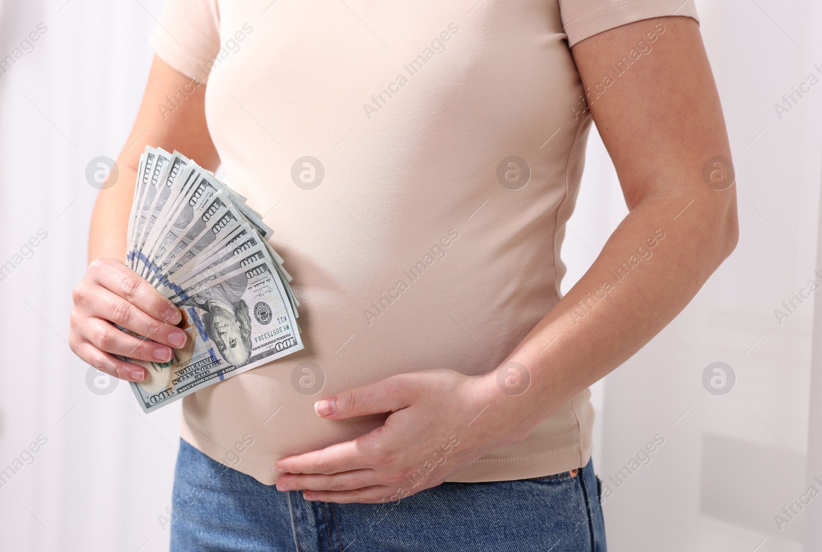 Photo of Surrogate mother. Pregnant woman with dollar banknotes indoors, closeup