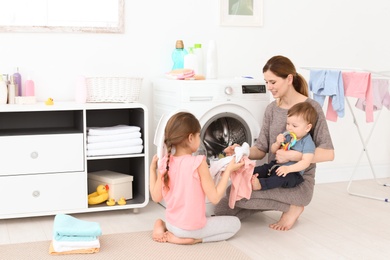 Housewife with little children doing laundry at home