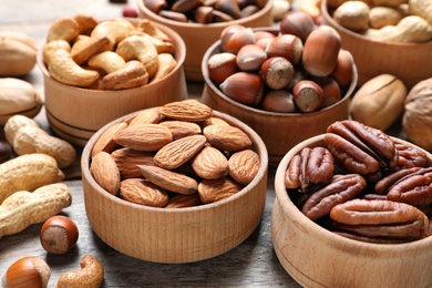 Photo of Bowls with organic nuts on wooden table. Snack mix