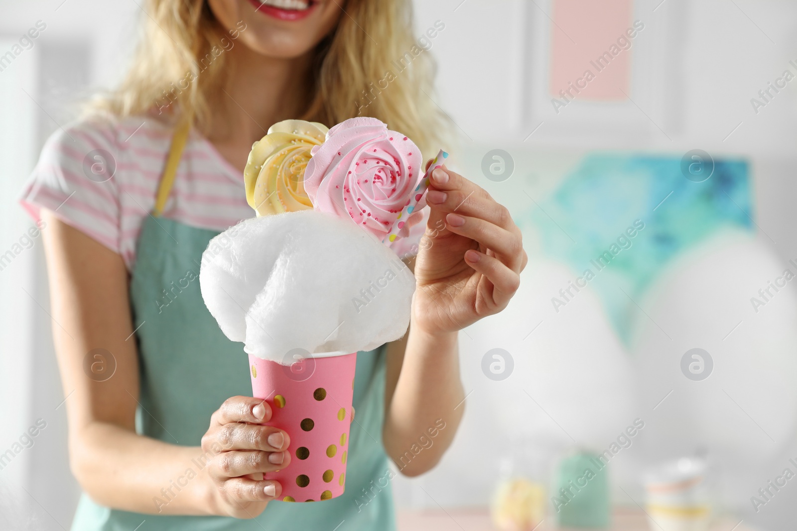 Photo of Young woman with cup of cotton candy dessert indoors, closeup. Space for text