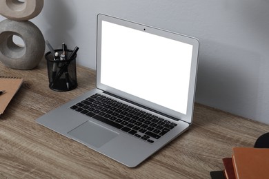 Comfortable workplace with modern laptop near light grey wall indoors. Space for design