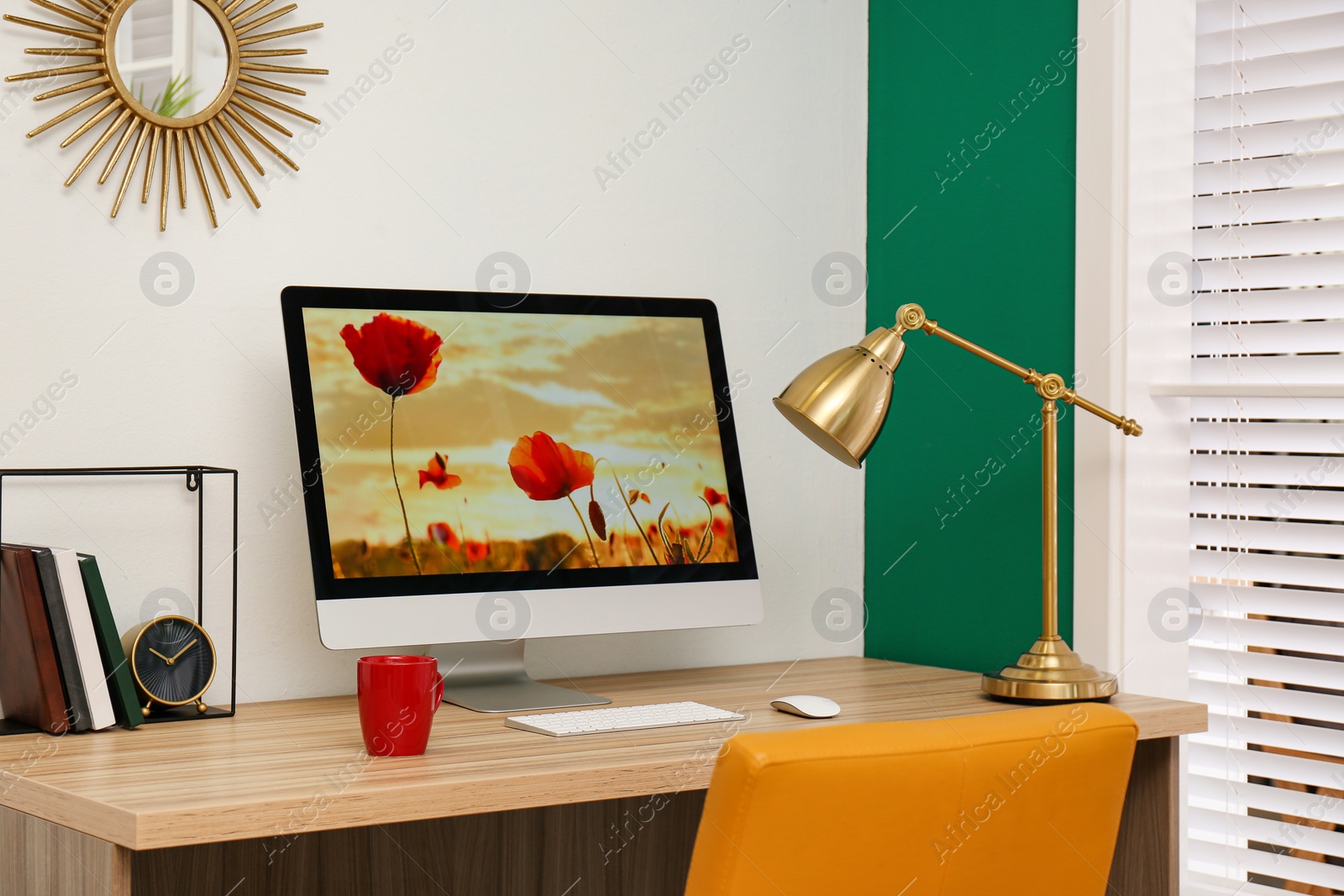 Photo of Comfortable workplace near window with white horizontal blinds in room