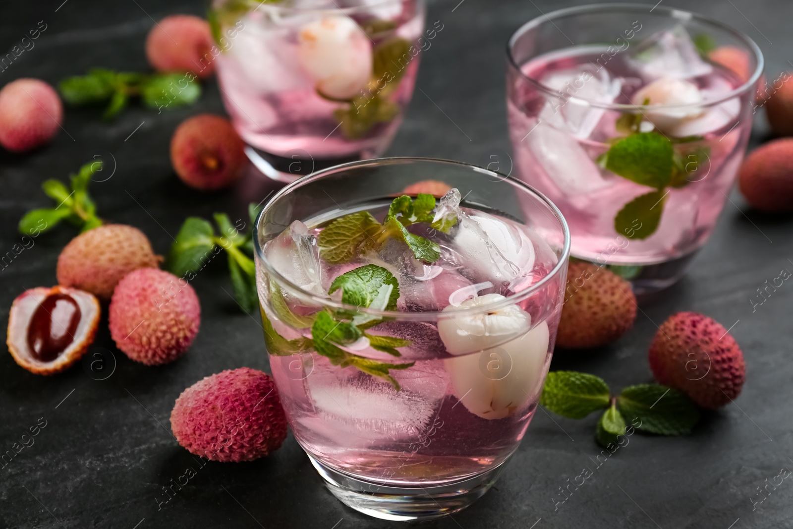 Photo of Delicious lychee cocktails with mint and fresh fruits on black table