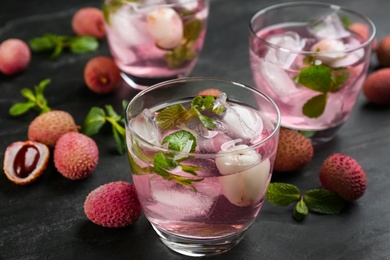 Delicious lychee cocktails with mint and fresh fruits on black table