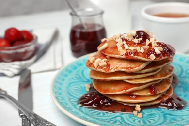 Photo of Delicious pancakes with jam and nuts on plate served for breakfast , closeup