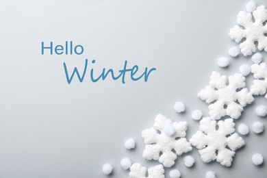 Image of Beautiful snowflakes, decorative balls and phrase Hello Winter on light background, flat lay
