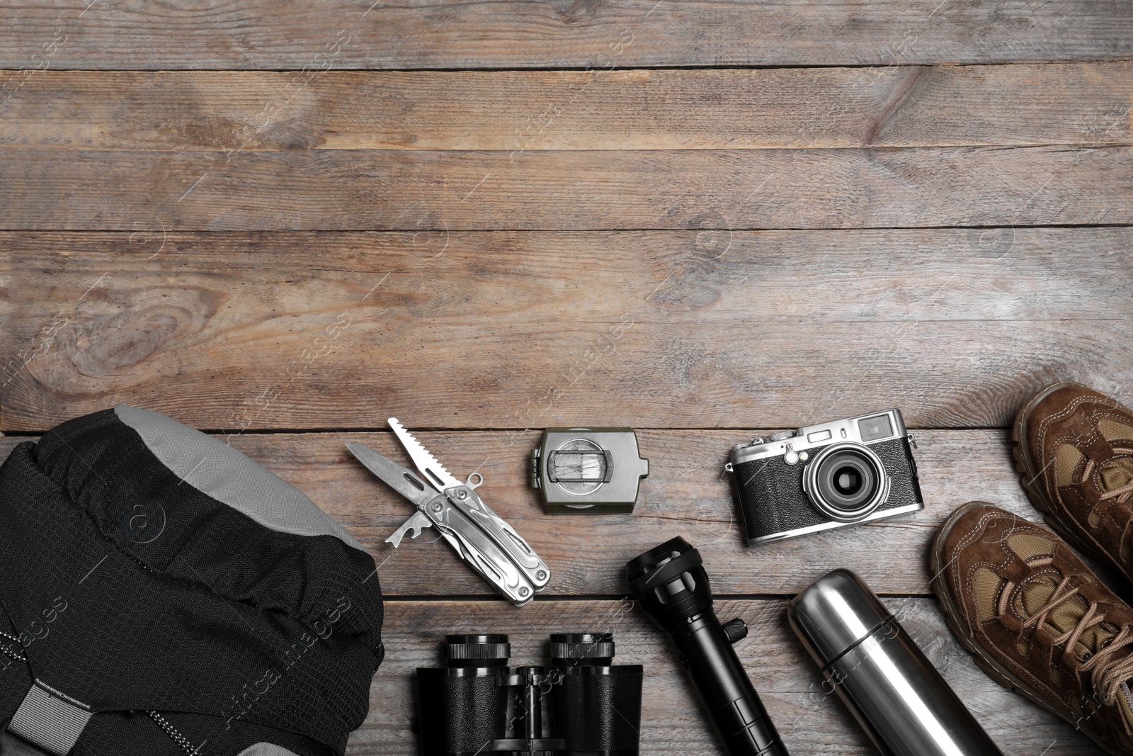 Photo of Flat lay composition with tourist backpack and other camping equipment on wooden background, space for text