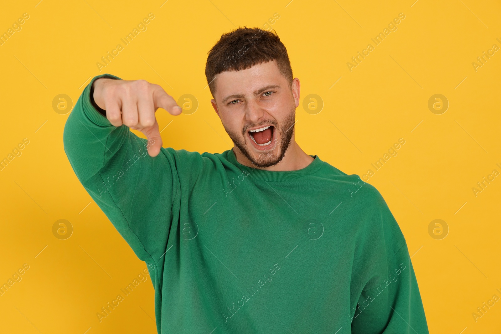 Photo of Aggressive young man shouting on orange background