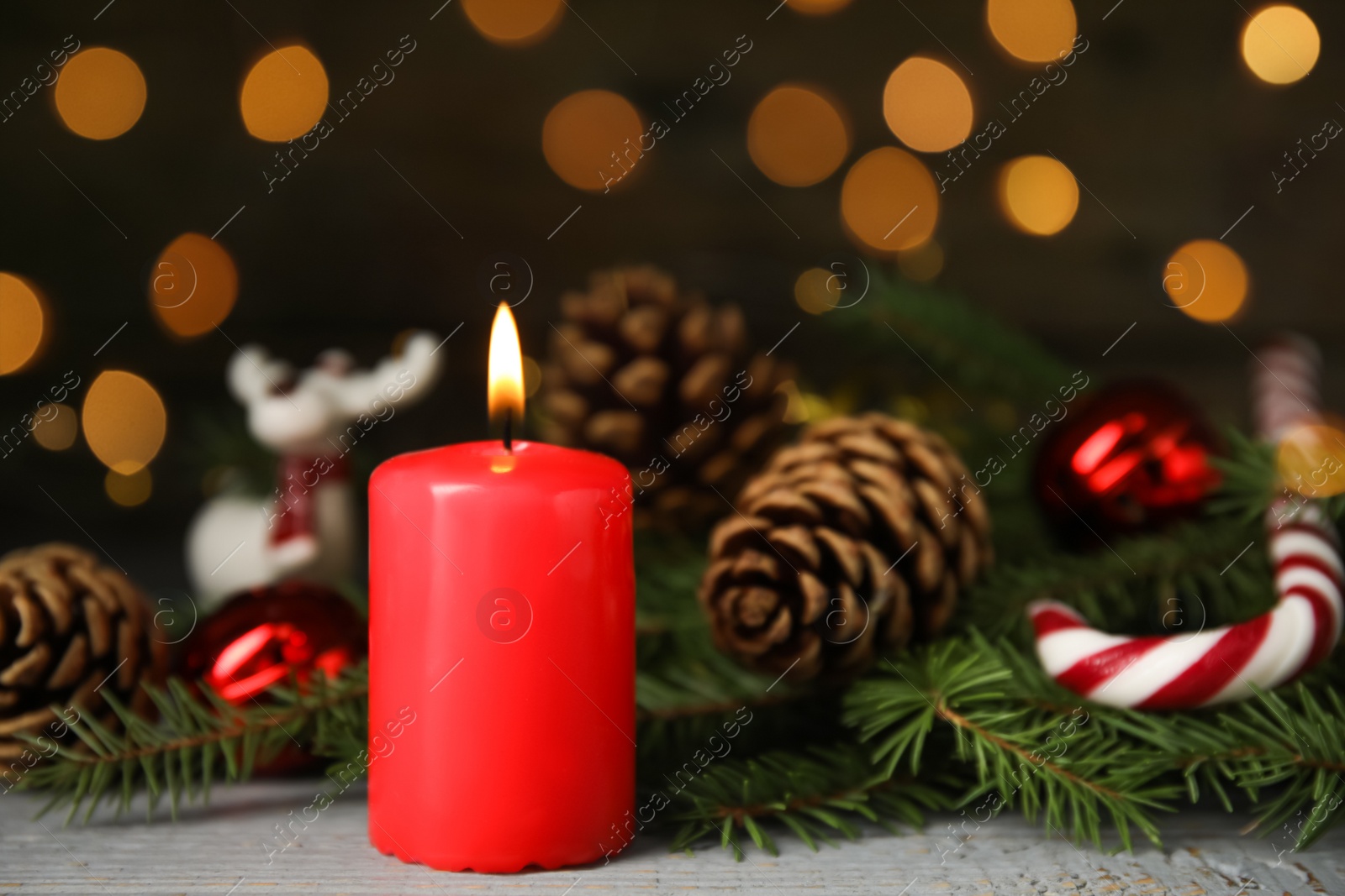 Photo of Burning candle and Christmas decor on wooden table against blurred festive lights, space for text 