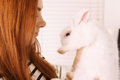 Woman with fluffy white rabbit indoors, closeup. Cute pet