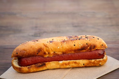 Photo of Fresh tasty hot dog on wooden table, closeup
