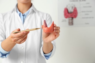 Endocrinologist showing thyroid gland model in hospital, closeup