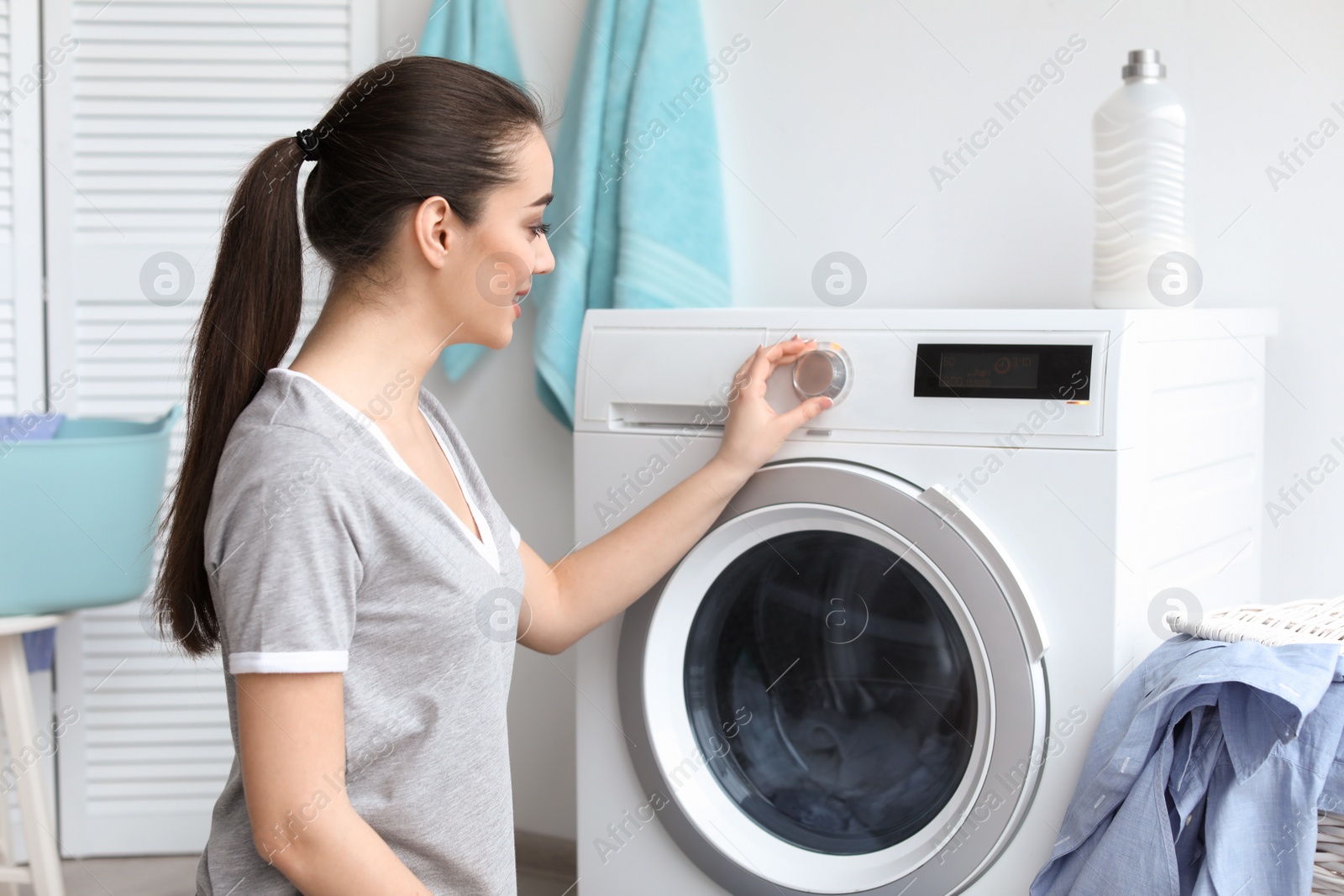 Photo of Young woman doing laundry at home