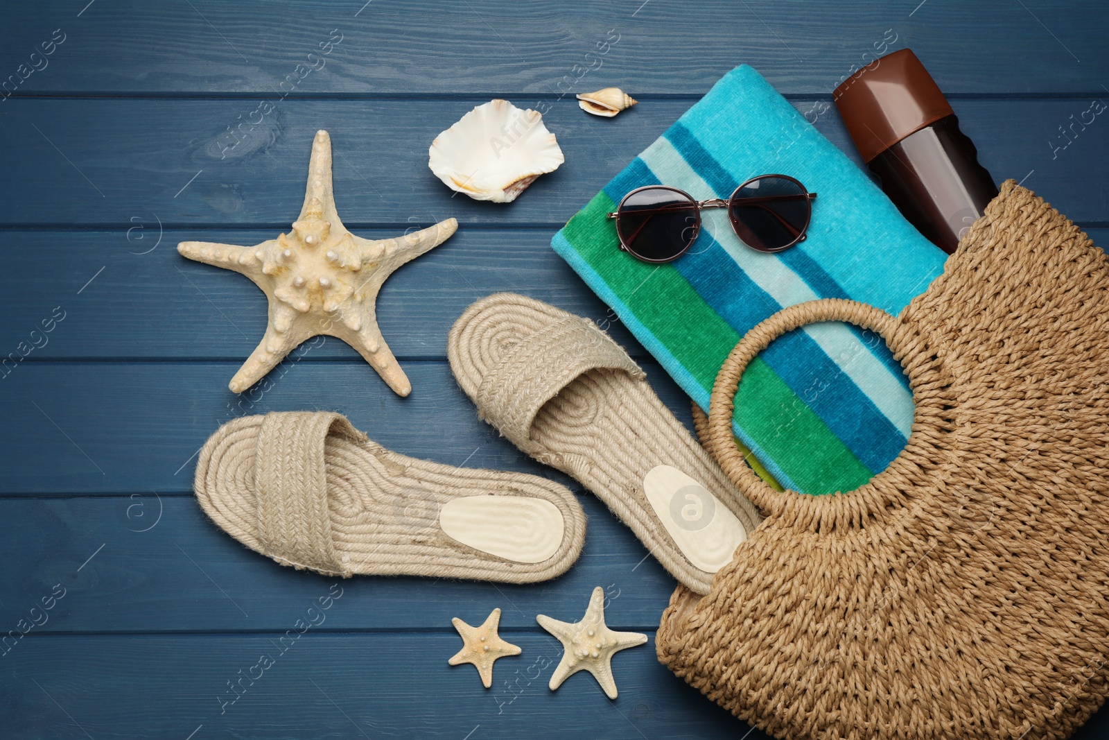 Photo of Stylish bag and beach accessories on blue wooden background, flat lay