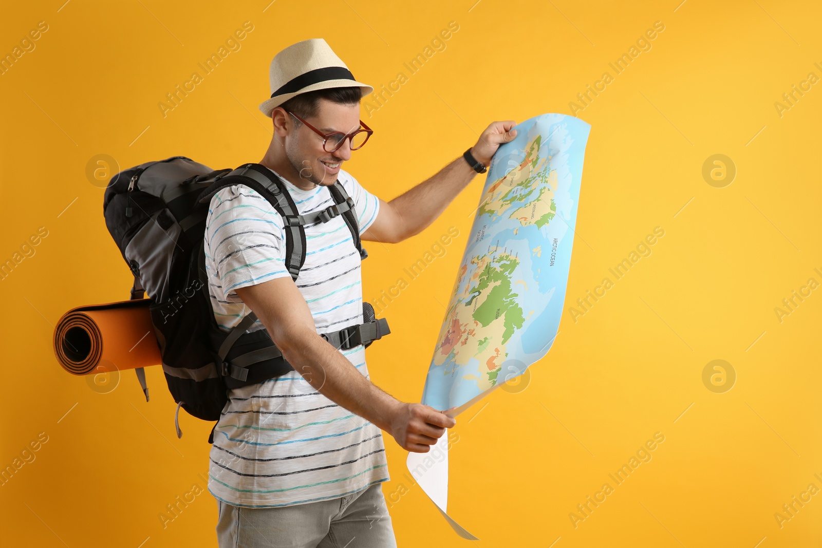 Photo of Male tourist with travel backpack and map on yellow background