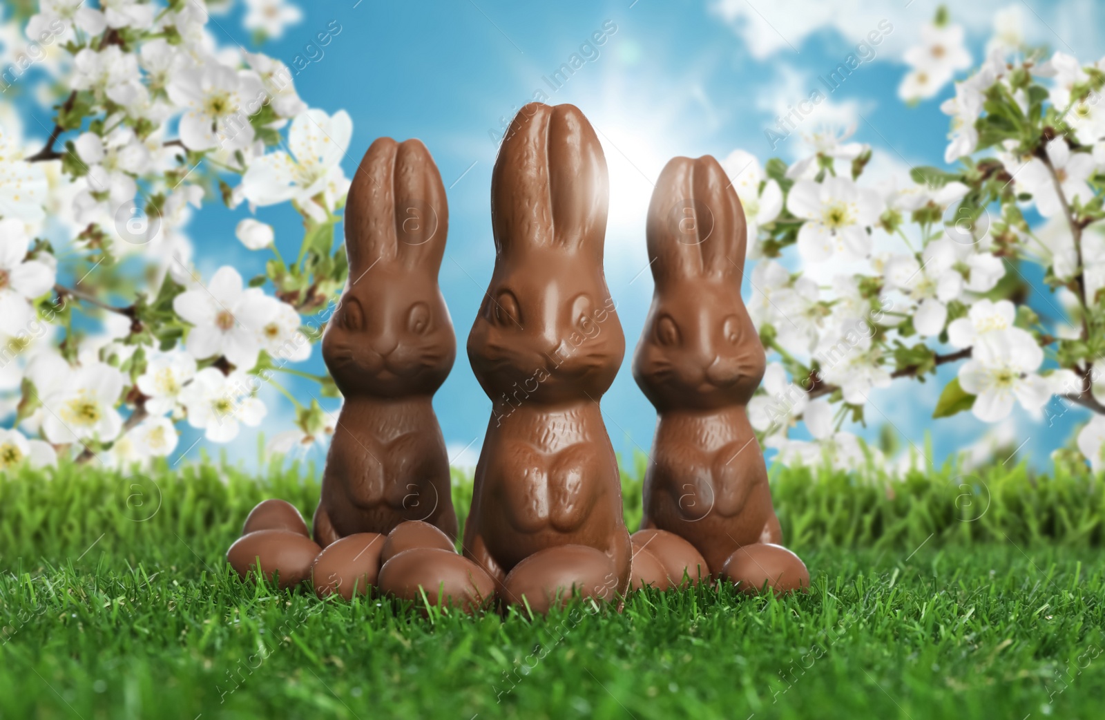 Image of Chocolate bunnies and eggs on green grass outdoors. Easter celebration