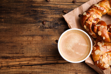 Delicious pastries and coffee on wooden table, flat lay. Space for text