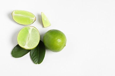 Photo of Fresh ripe limes and leaves on white background, flat lay. Space for text