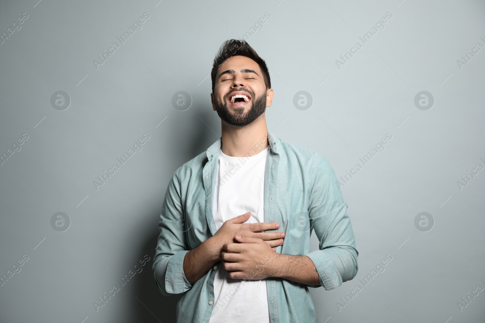 Photo of Young man laughing on light grey background. Funny joke