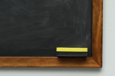 Dirty black chalkboard with duster hanging on grey wall
