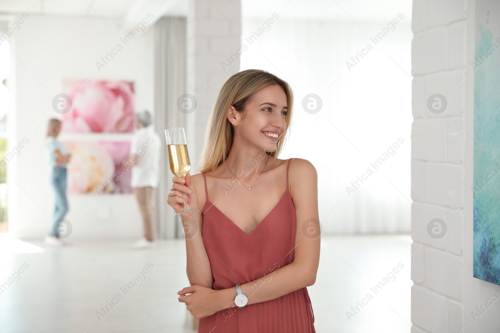 Photo of Young woman with glass of champagne at exhibition in art gallery