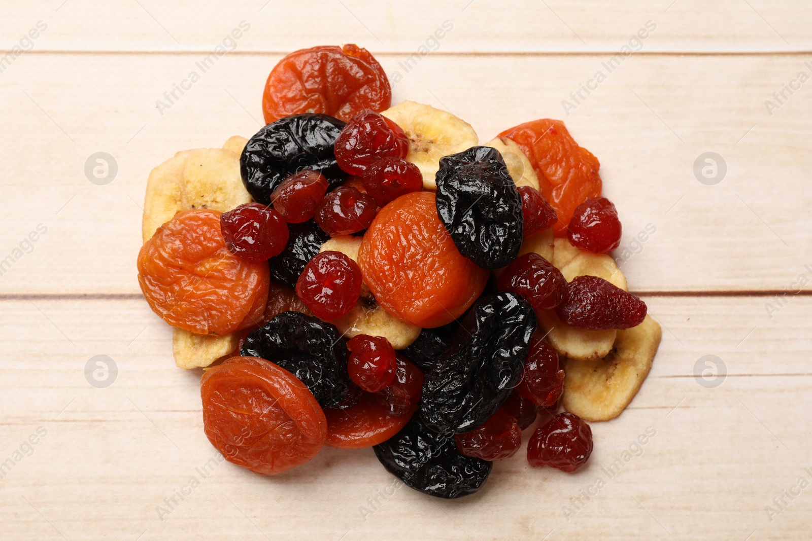 Photo of Mix of delicious dried fruits on white wooden table, top view