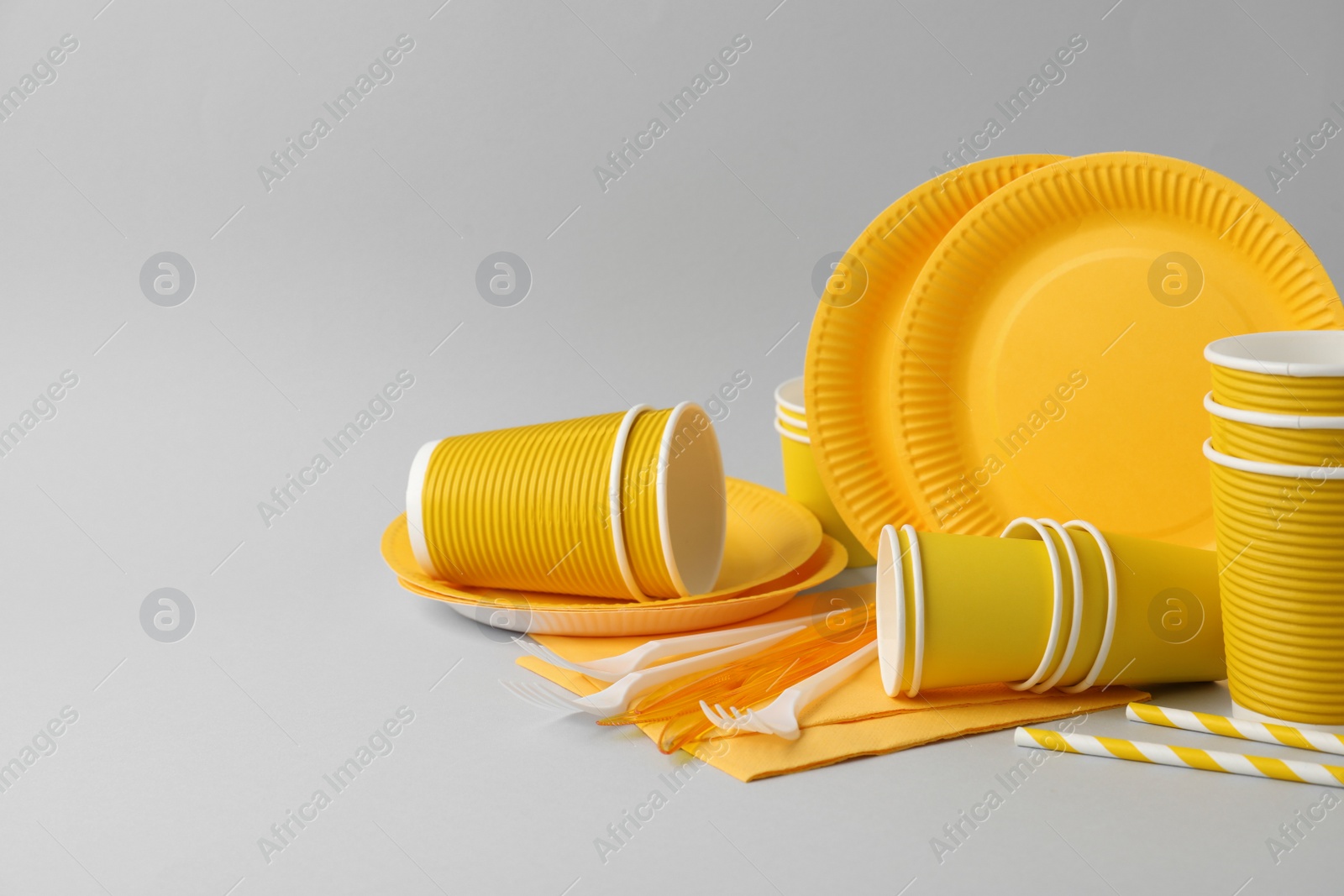 Photo of Disposable tableware on light grey background. Space for text