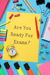 Yellow paper with question Are you ready for exams and stationery on light blue table, flat lay