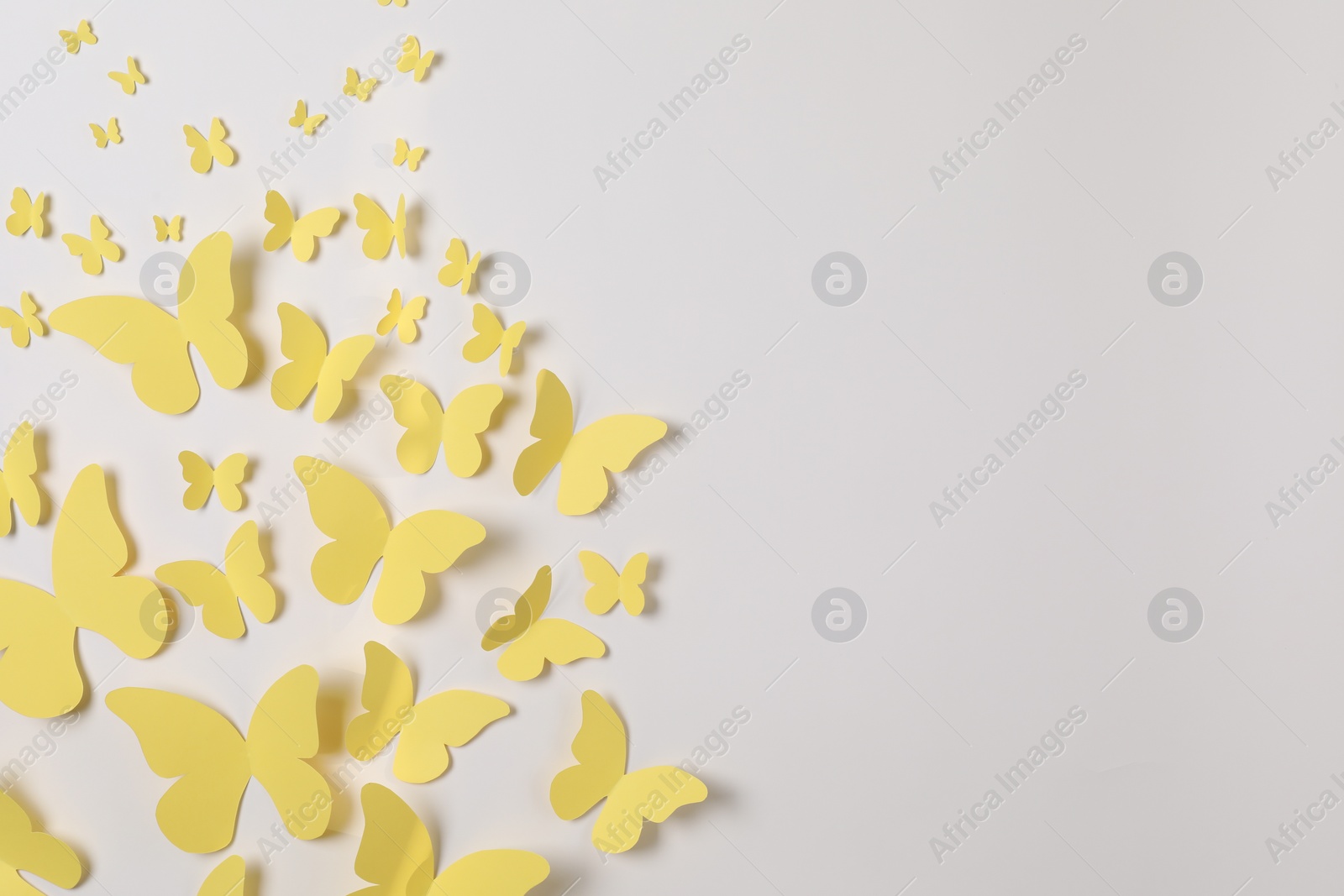 Photo of Yellow paper butterflies on white background, top view. Space for text