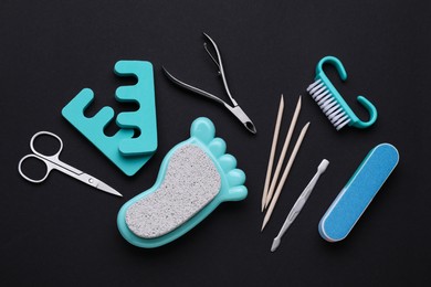 Photo of Set of pedicure tools on black background, flat lay