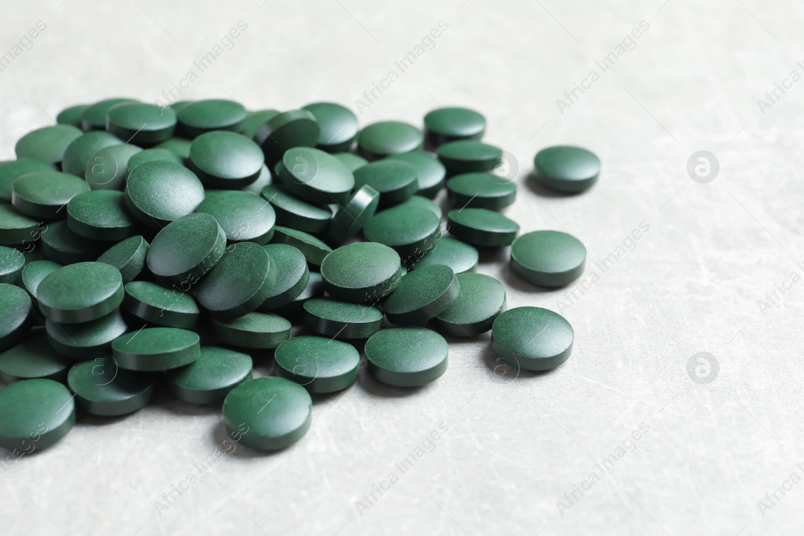 Photo of Heap of green spirulina pills on light table