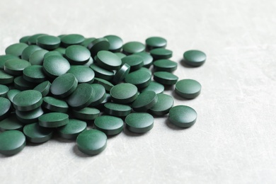 Photo of Heap of green spirulina pills on light table