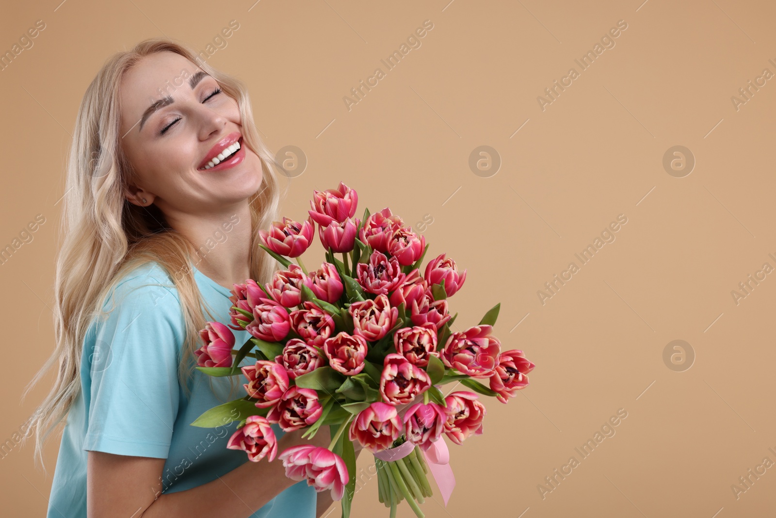 Photo of Happy young woman with beautiful bouquet on beige background. Space for text