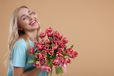 Happy young woman with beautiful bouquet on beige background. Space for text